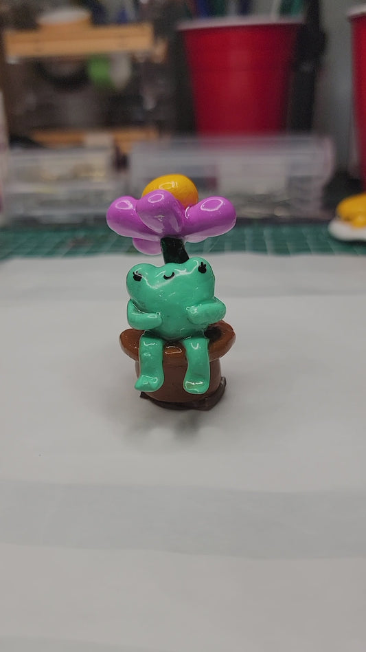 baby frog sitting under a flower desk & dash buddy